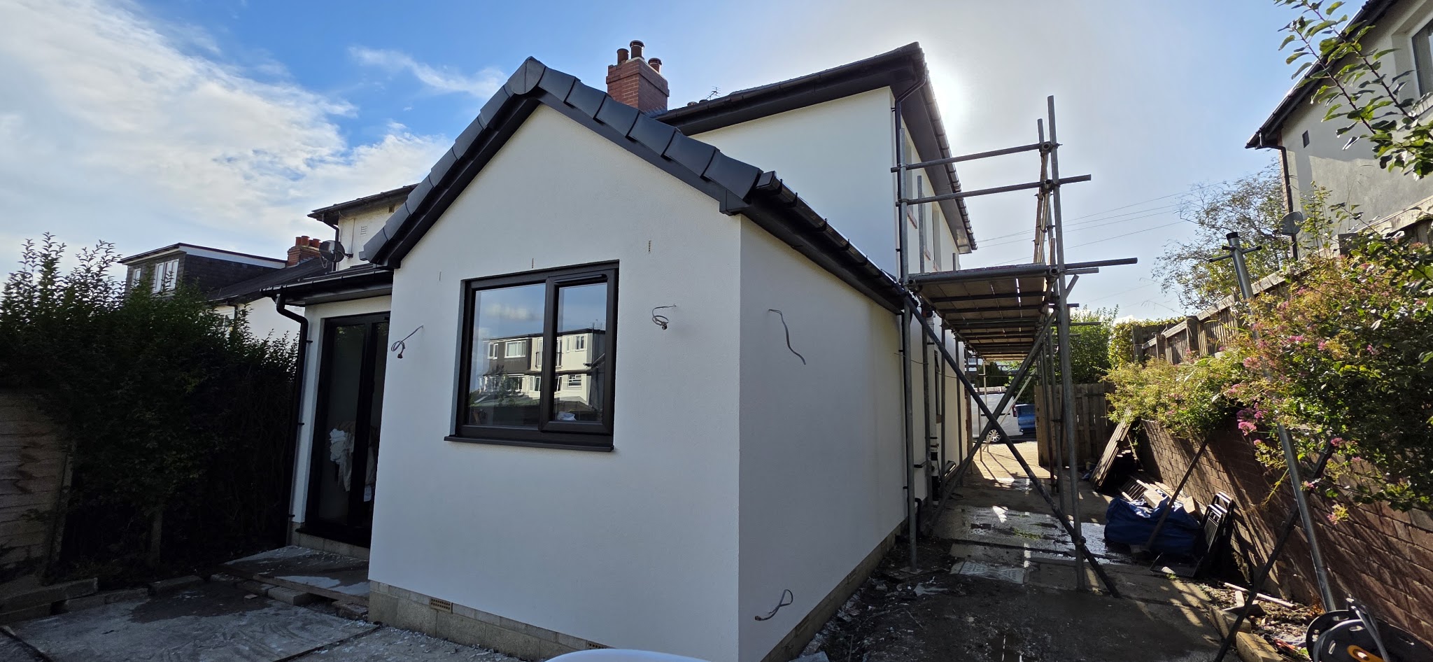 White rendered house with dark window frames and side scaffolding