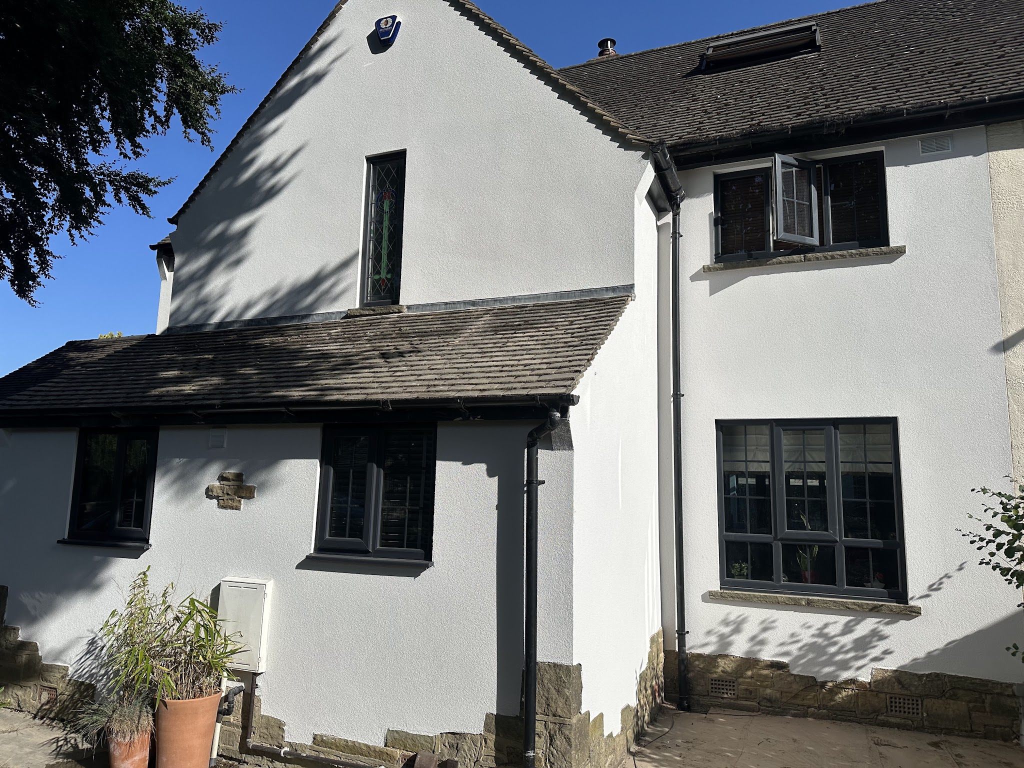 Finished white render, dark windows and retained stone features on a customer's house