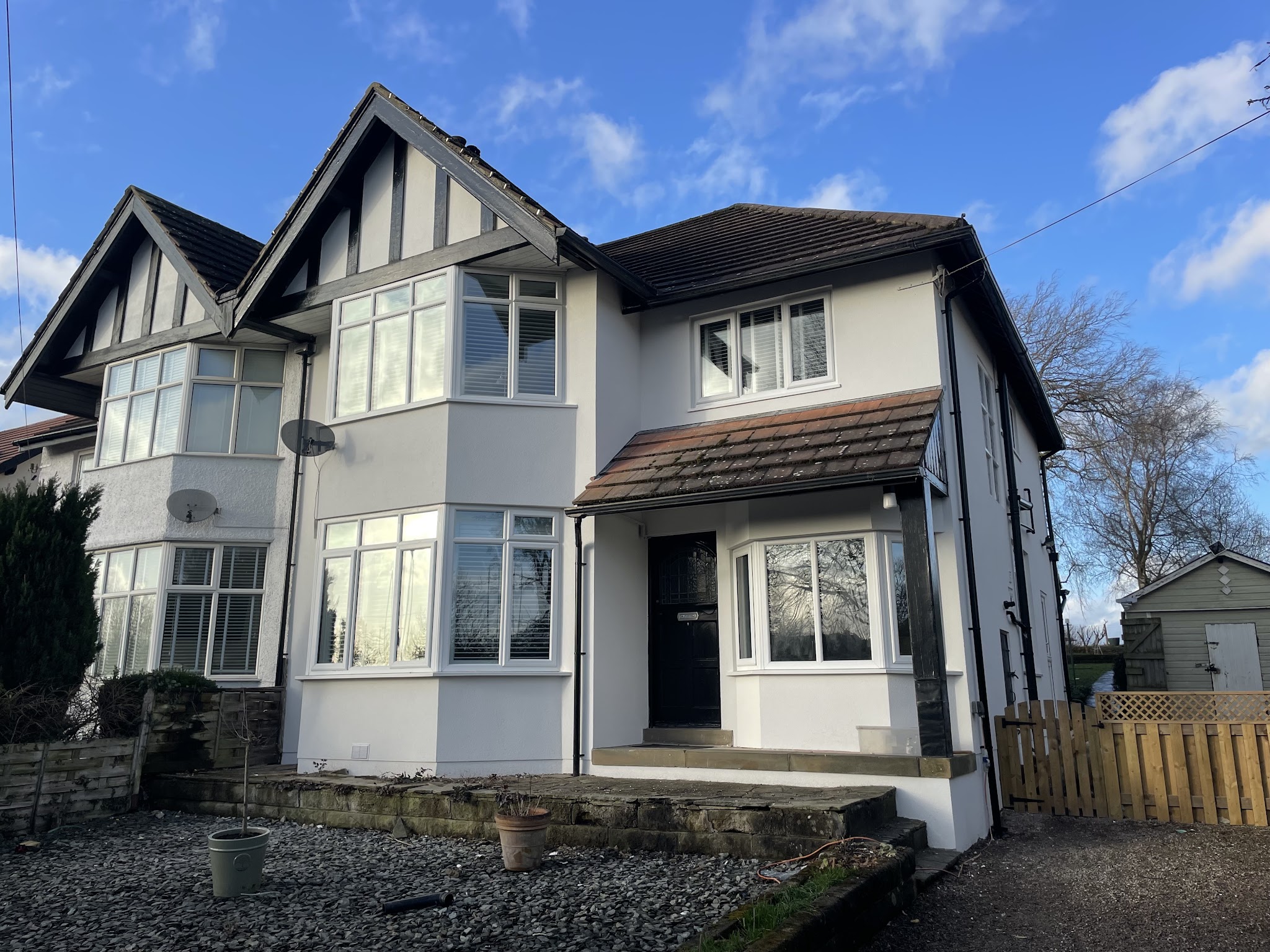 Completed pale rendering on a semi-detached home, with bay windows and black timber details